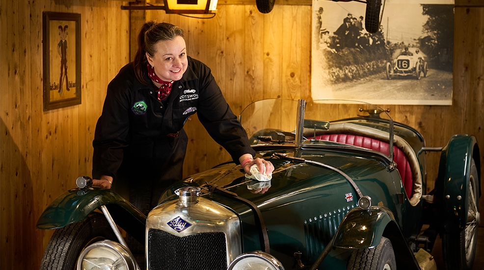 Isabel Harvey, manager at the Cotswold Motoring and Toy Museum, posing while polishing the Brooklands Riley 9